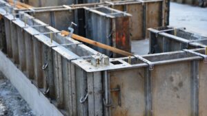 Metal concrete formwork foundation repair panels are set up at a construction site, prepared for pouring a concrete foundation.
