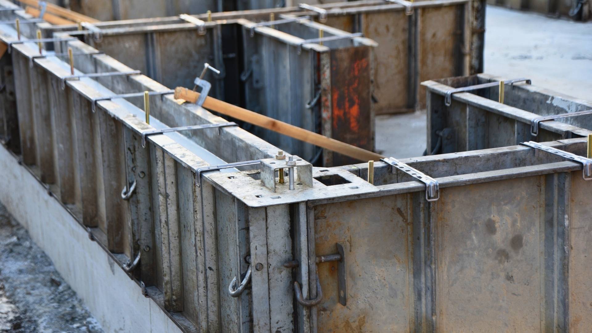 Metal concrete formwork foundation repair panels are set up at a construction site, prepared for pouring a concrete foundation.